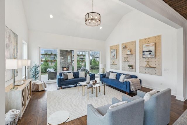 living room featuring a chandelier, high vaulted ceiling, a fireplace, and dark wood-type flooring