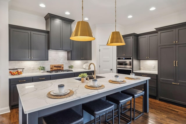 kitchen with light stone counters, an island with sink, and dark wood-type flooring