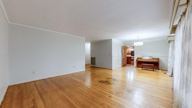 unfurnished living room with light hardwood / wood-style flooring, a notable chandelier, and crown molding