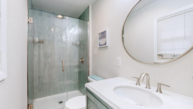 bathroom with vanity, toilet, and a shower with door