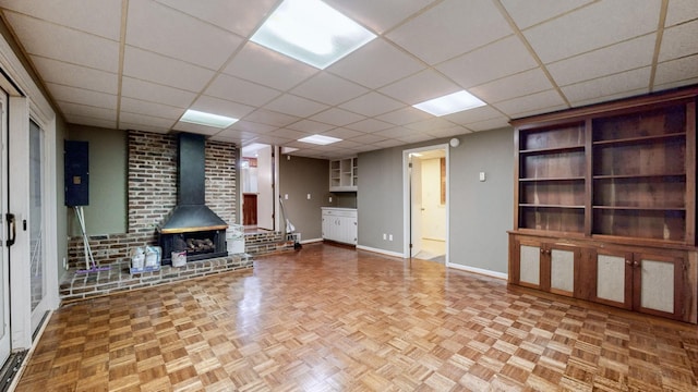 unfurnished living room with parquet flooring, a paneled ceiling, and a wood stove