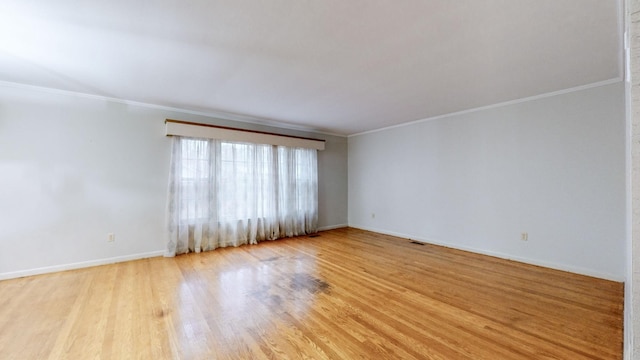 empty room featuring light wood-type flooring and crown molding