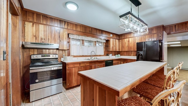 kitchen with sink, black appliances, range hood, a kitchen island, and wood walls