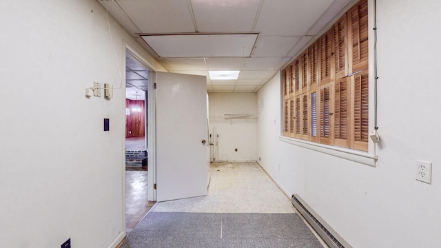 corridor featuring baseboard heating and a drop ceiling