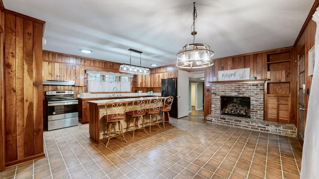 kitchen with black fridge, sink, stainless steel range with electric cooktop, and wood walls