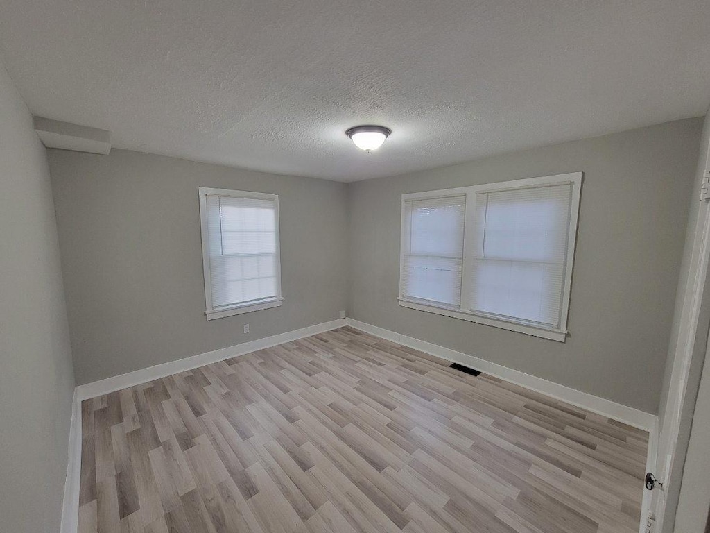 spare room featuring a textured ceiling and light hardwood / wood-style flooring