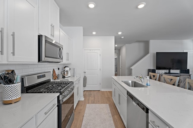 kitchen with white cabinets, appliances with stainless steel finishes, light hardwood / wood-style floors, and sink