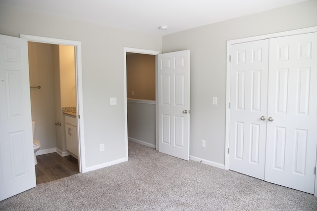 unfurnished bedroom with carpet flooring, ensuite bathroom, and a closet