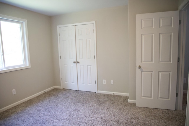 unfurnished bedroom featuring carpet flooring, a closet, and multiple windows