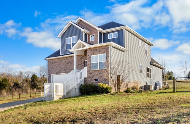 view of front of house featuring a front lawn, cooling unit, and a garage