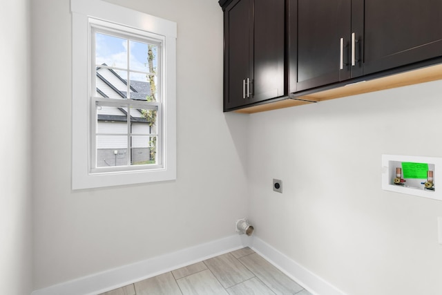 washroom with washer hookup, electric dryer hookup, and cabinets