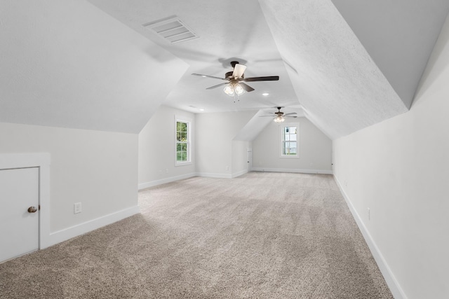 additional living space with light carpet, a wealth of natural light, and ceiling fan