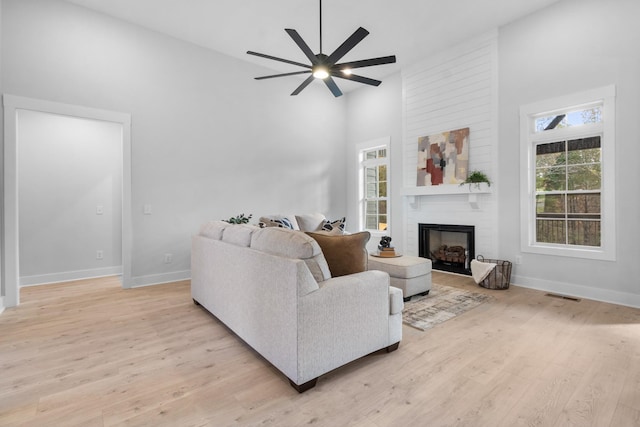 living room with a fireplace, plenty of natural light, and light wood-type flooring