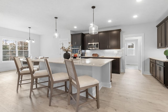 kitchen featuring a center island with sink, light hardwood / wood-style floors, and pendant lighting