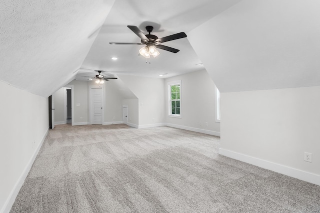 bonus room featuring a textured ceiling, ceiling fan, light carpet, and vaulted ceiling