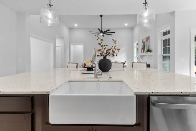 kitchen with decorative light fixtures, stainless steel dishwasher, and light stone counters