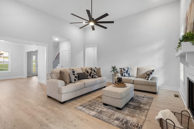 living room with ceiling fan, light hardwood / wood-style floors, and high vaulted ceiling