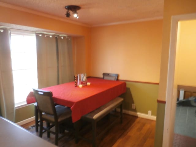 dining room with ornamental molding, dark hardwood / wood-style floors, a textured ceiling, and a wealth of natural light