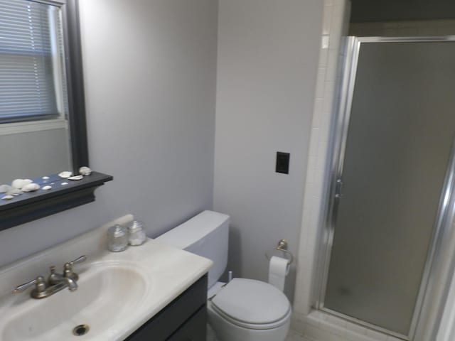 bathroom featuring a shower with door, vanity, and toilet