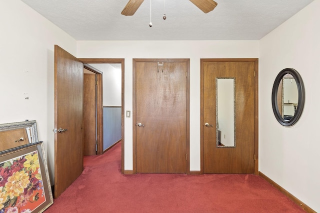 bedroom with dark colored carpet, a textured ceiling, ceiling fan, and multiple closets