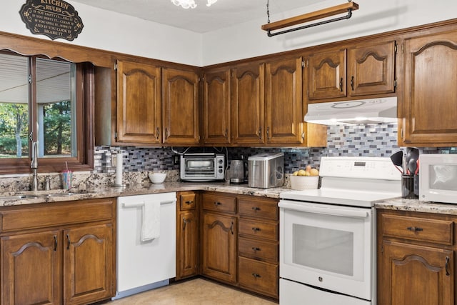 kitchen with backsplash, light stone counters, sink, and white appliances