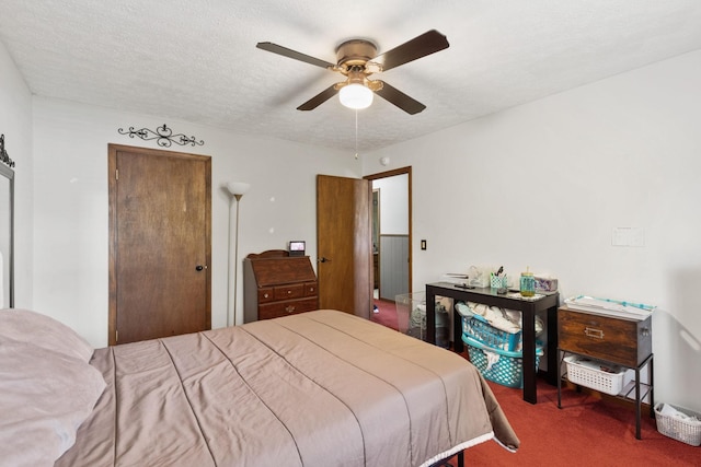 bedroom with ceiling fan, a textured ceiling, and dark colored carpet