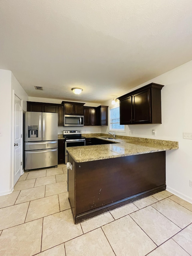 kitchen featuring kitchen peninsula, dark brown cabinets, stainless steel appliances, and sink