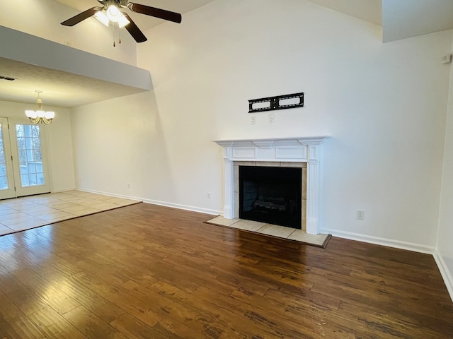 unfurnished living room featuring ceiling fan with notable chandelier, a fireplace, and light hardwood / wood-style flooring