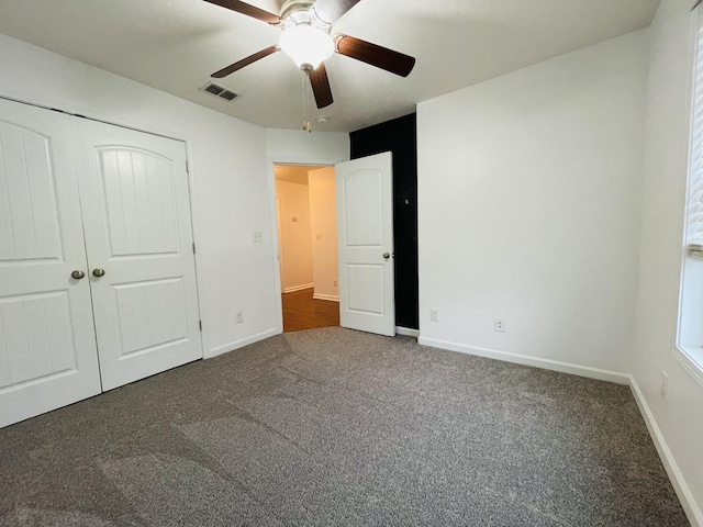 unfurnished bedroom featuring ceiling fan, dark carpet, and a closet