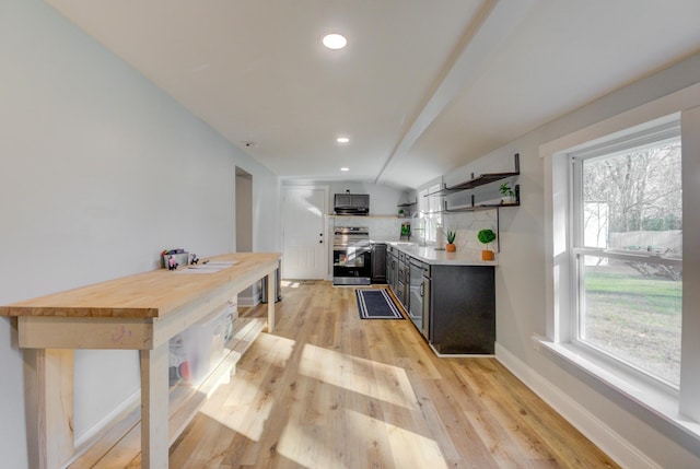 kitchen with wood counters, backsplash, light hardwood / wood-style flooring, vaulted ceiling, and stainless steel appliances