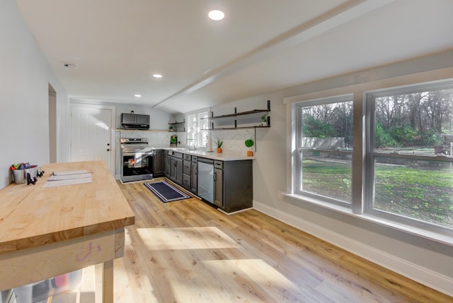 kitchen with tasteful backsplash, stainless steel appliances, vaulted ceiling, and light wood-type flooring