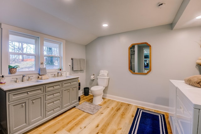 bathroom with vanity, vaulted ceiling, hardwood / wood-style flooring, washing machine and dryer, and toilet