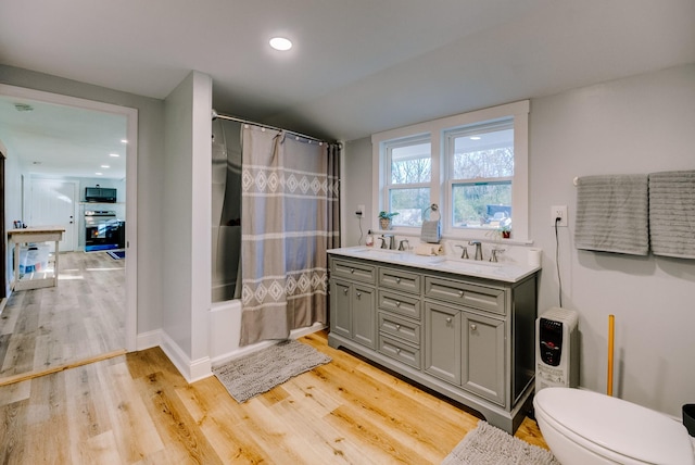 full bathroom with hardwood / wood-style floors, vanity, toilet, and shower / tub combo