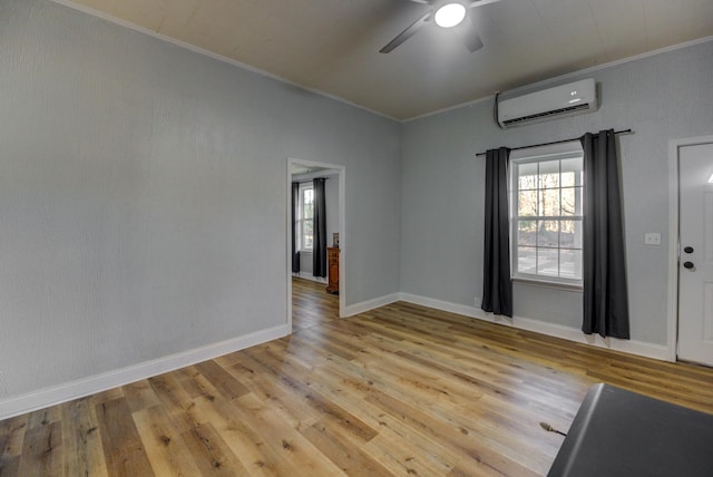 unfurnished room featuring a wall unit AC, ceiling fan, light hardwood / wood-style flooring, and ornamental molding