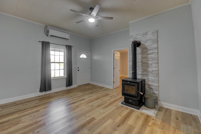 unfurnished living room with a wood stove, crown molding, light hardwood / wood-style flooring, ceiling fan, and a wall mounted AC