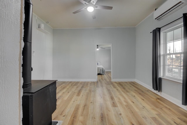 interior space with a wood stove, an AC wall unit, ceiling fan, light wood-type flooring, and ornamental molding