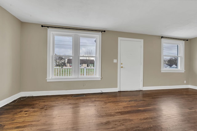 spare room with plenty of natural light and dark hardwood / wood-style flooring