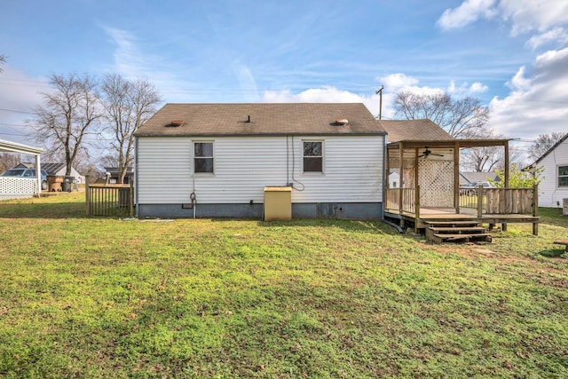 rear view of property featuring a lawn, ceiling fan, and a wooden deck