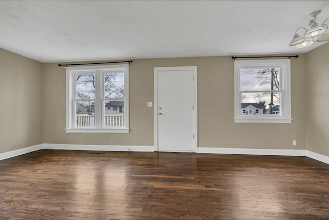 foyer with dark wood-type flooring and an inviting chandelier