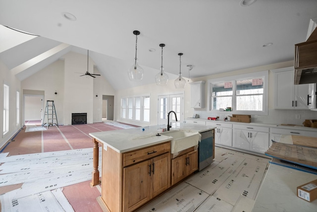 kitchen with white cabinetry, sink, ceiling fan, stainless steel dishwasher, and a kitchen island with sink