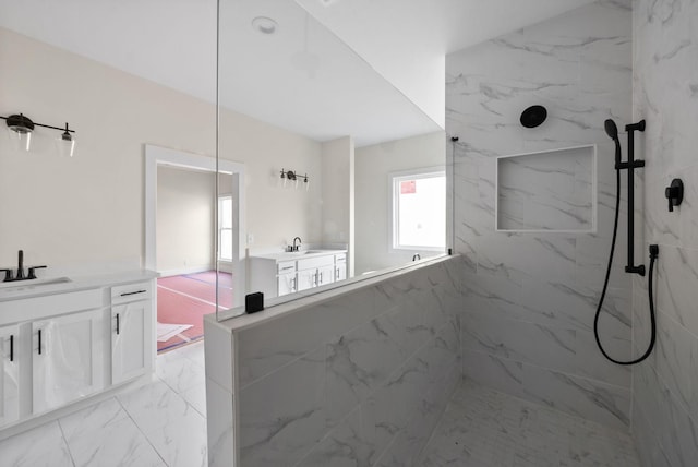 bathroom with a tile shower and vanity