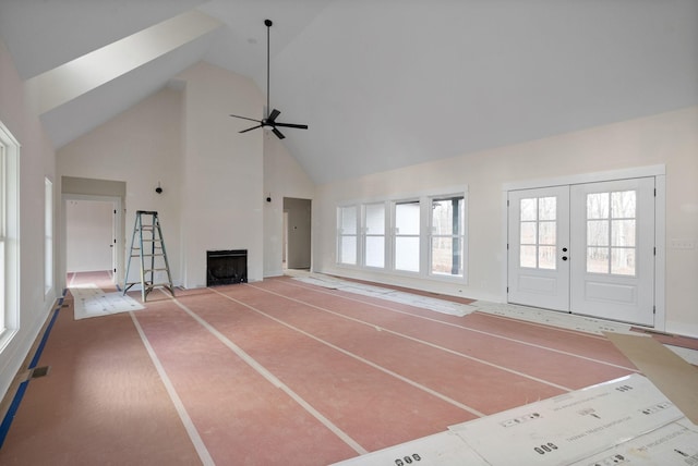 unfurnished living room featuring french doors, high vaulted ceiling, and ceiling fan