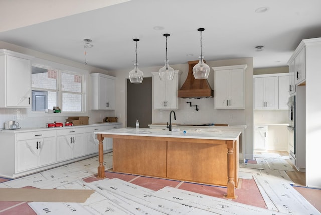 kitchen featuring white cabinetry, a center island with sink, pendant lighting, and light hardwood / wood-style flooring