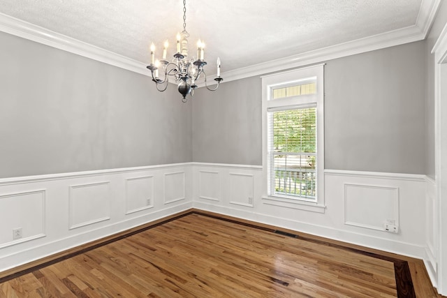 empty room with ornamental molding, a chandelier, a textured ceiling, and wood-type flooring