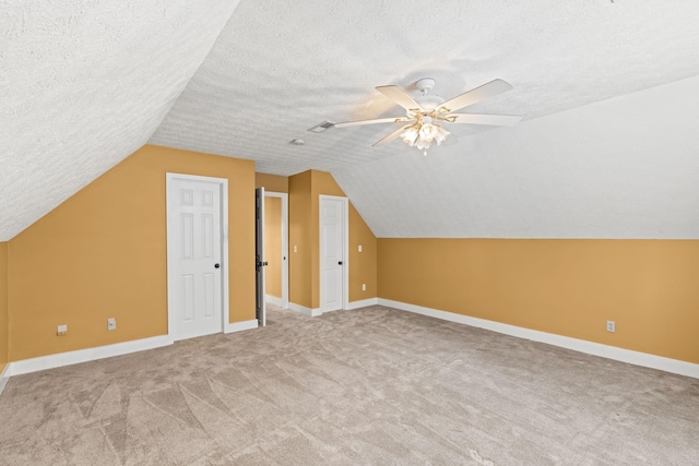 bonus room featuring vaulted ceiling, ceiling fan, carpet, and a textured ceiling