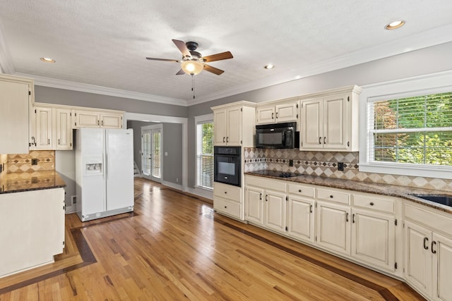 kitchen with crown molding, a wealth of natural light, light hardwood / wood-style flooring, and black appliances