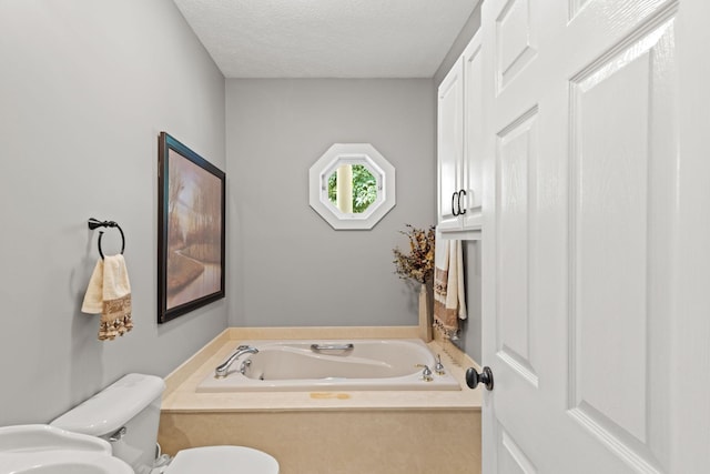 bathroom featuring a bath, a textured ceiling, and toilet