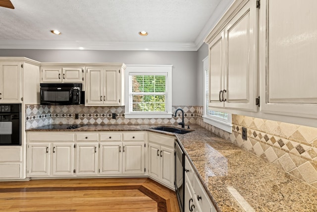 kitchen featuring sink, light hardwood / wood-style flooring, crown molding, white cabinets, and black appliances