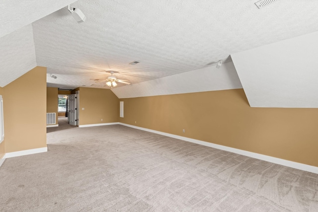 additional living space with carpet flooring, lofted ceiling, ceiling fan, and a textured ceiling