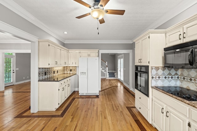 kitchen with black appliances, light hardwood / wood-style floors, dark stone countertops, and tasteful backsplash